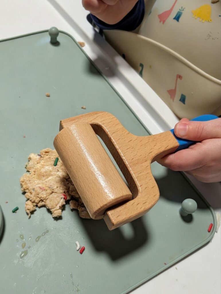 A toddler rolling dough